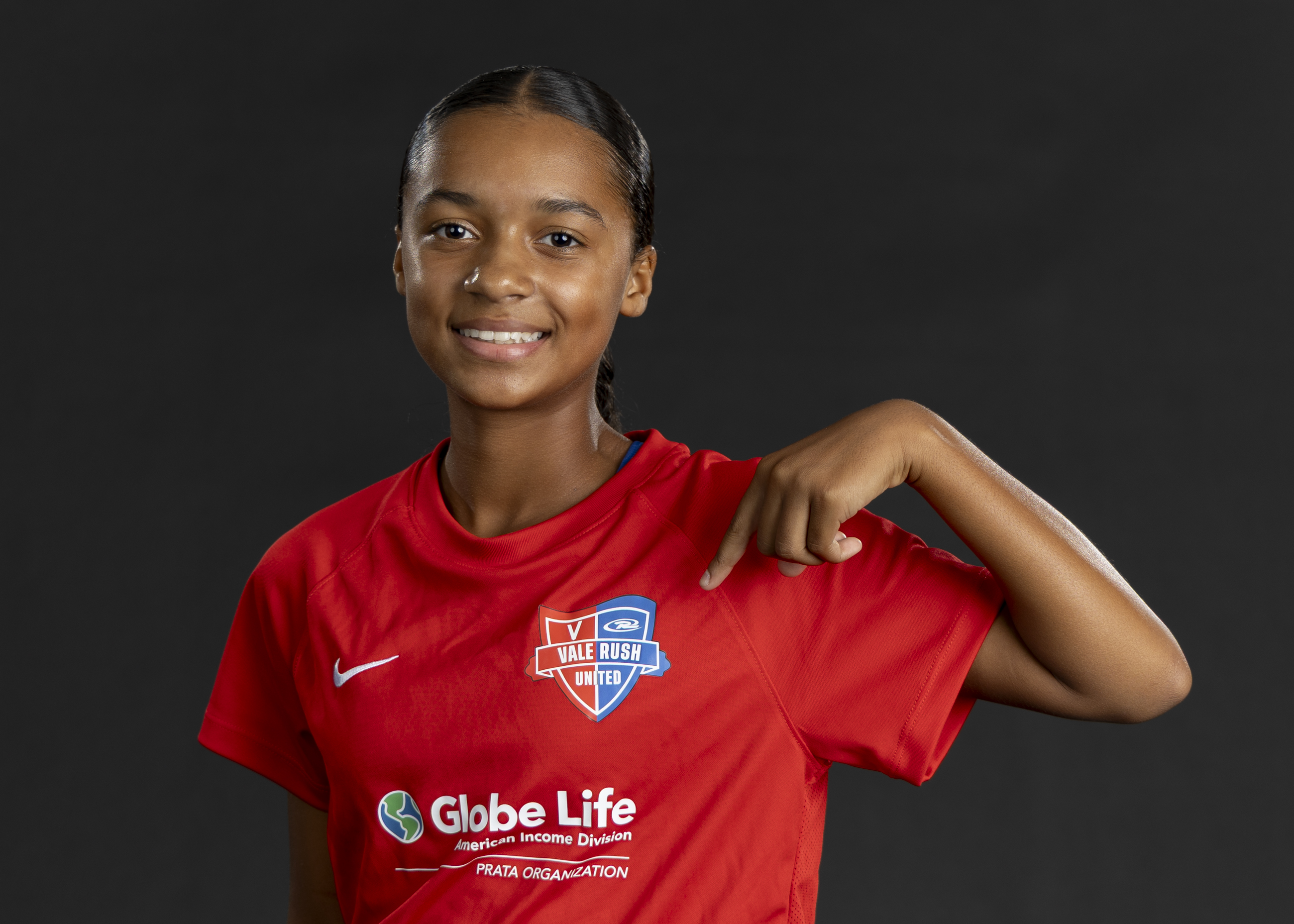 Vale Rush United player proudly pointing to the club badge on her jersey